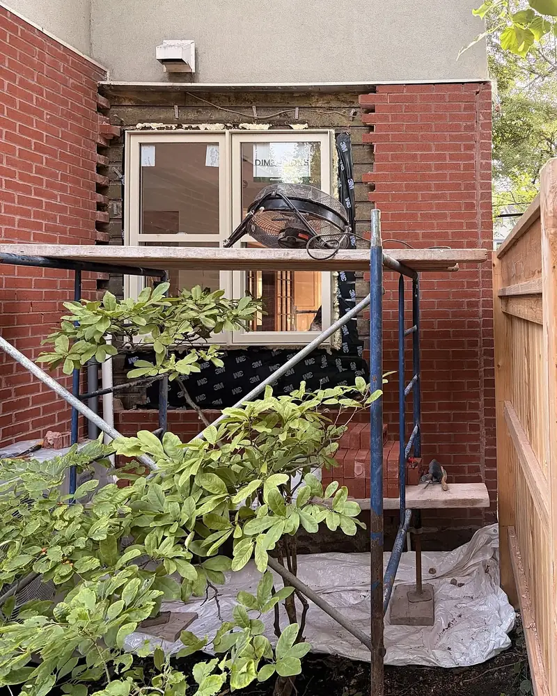 Même mur pendant les travaux : brique retirée autour de la fenêtre, échafaudage en place