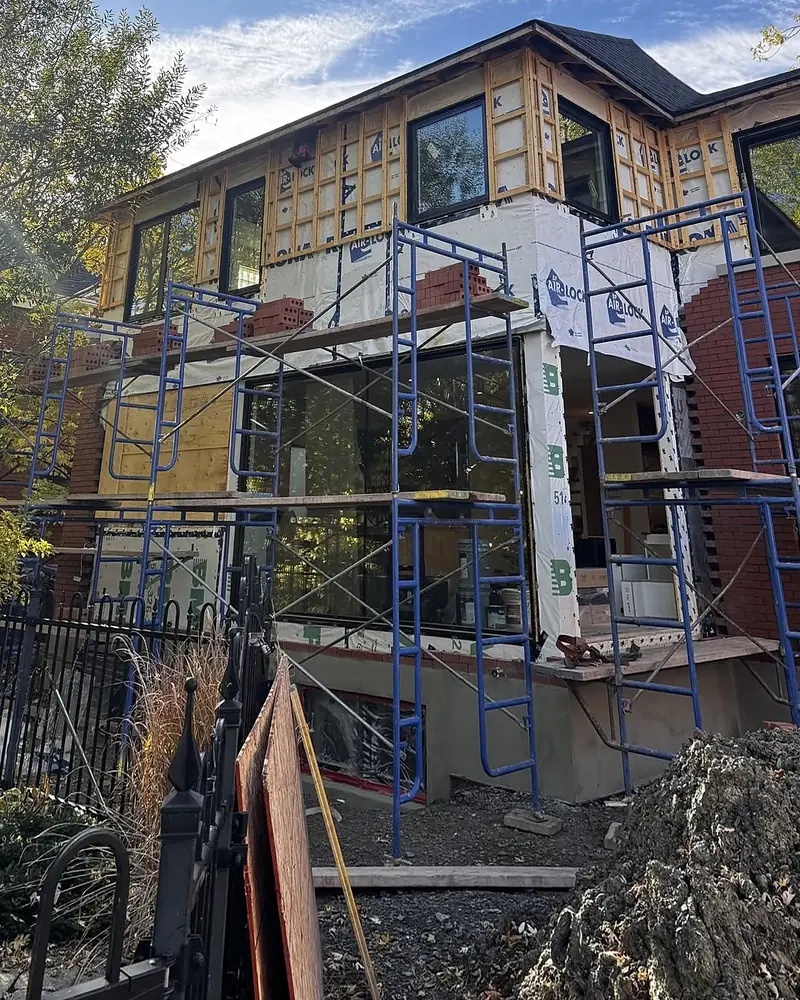 Même maison pendant les travaux : échafaudages, pare-air et palettes de brique